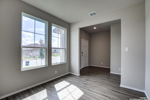 empty room featuring wood finished floors, baseboards, and visible vents