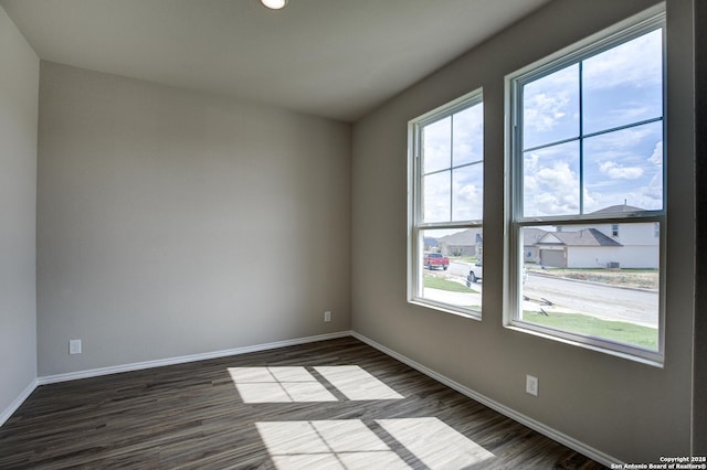 empty room featuring baseboards and dark wood-style flooring