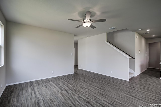 unfurnished living room featuring visible vents, baseboards, stairway, dark wood-style floors, and a ceiling fan