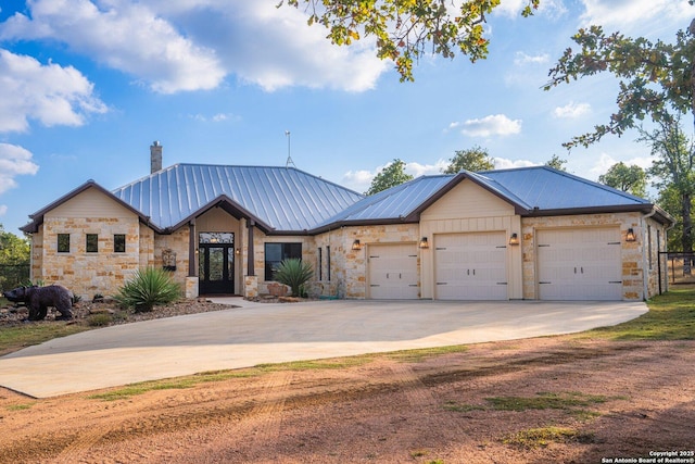 view of front facade with concrete driveway, a garage, stone siding, and metal roof