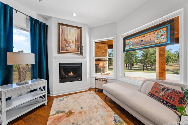 sitting room with a glass covered fireplace, wood finished floors, and baseboards