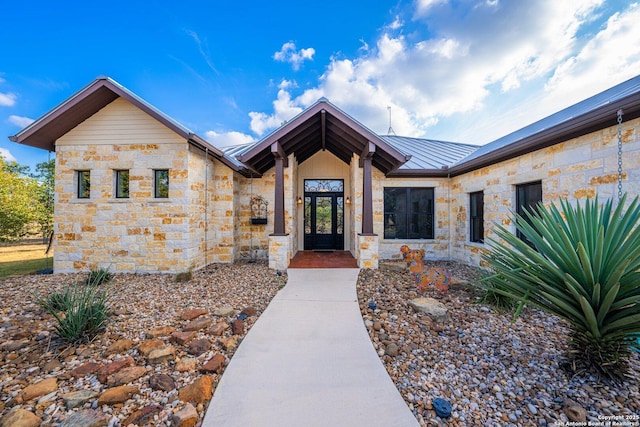 doorway to property with a standing seam roof, stone siding, and metal roof