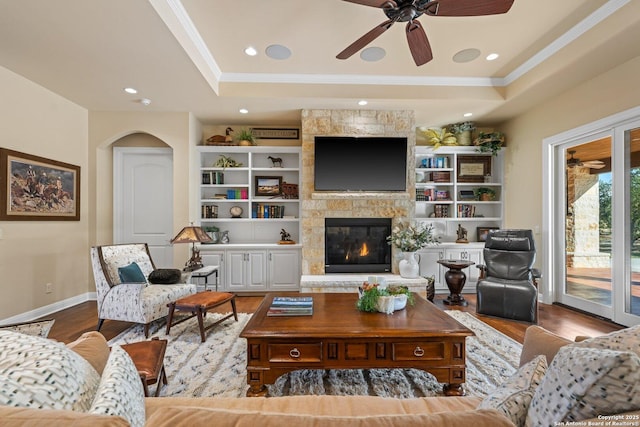 living area with crown molding, a raised ceiling, and wood finished floors