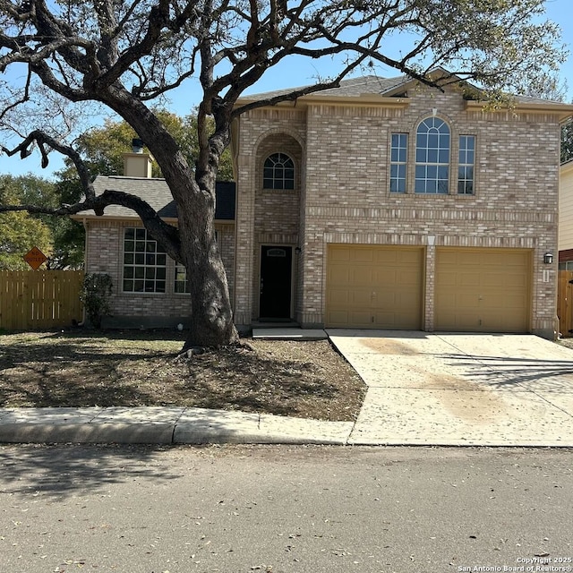 traditional home featuring a garage, fence, brick siding, and driveway