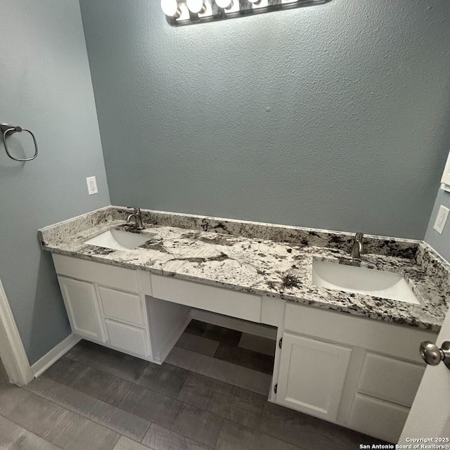 bathroom with double vanity, baseboards, and a sink