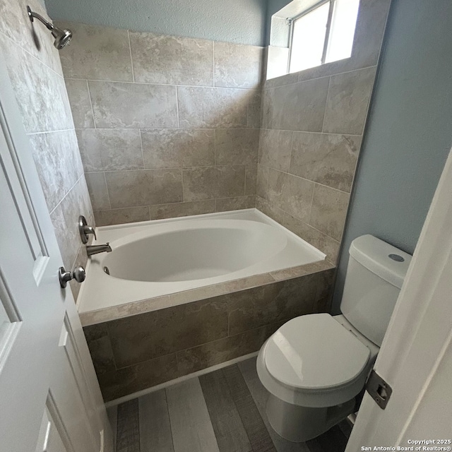 bathroom with toilet, wood finished floors, and shower / tub combination