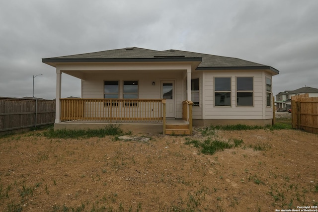 back of property featuring covered porch and fence