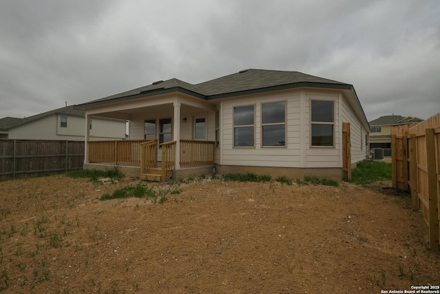 rear view of house with central AC unit, fence, and covered porch