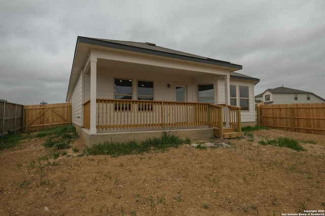 rear view of property with a porch and fence