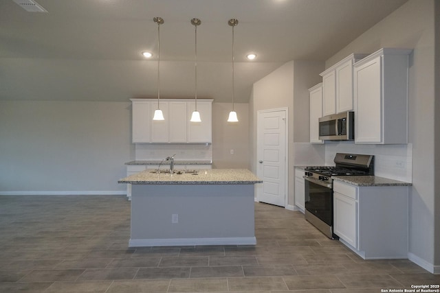 kitchen with a center island with sink, a sink, decorative light fixtures, white cabinetry, and appliances with stainless steel finishes