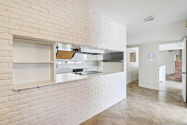 kitchen with visible vents, a sink, ventilation hood, brick wall, and tile patterned flooring