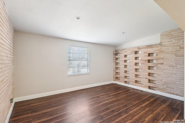 unfurnished room with lofted ceiling, baseboards, and dark wood-style flooring