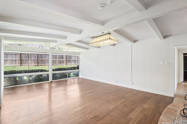 interior space featuring lofted ceiling with beams, wood finished floors, and baseboards