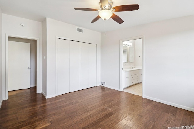 unfurnished bedroom with a closet, visible vents, baseboards, and wood finished floors