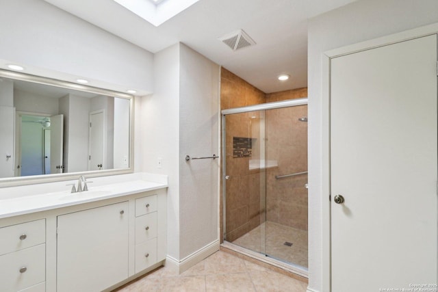 bathroom featuring tile patterned floors, visible vents, a stall shower, a skylight, and vanity