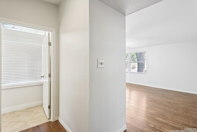 hallway featuring wood finished floors and baseboards