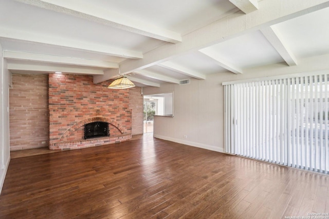 unfurnished living room with visible vents, baseboards, beam ceiling, a fireplace, and wood finished floors