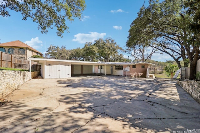 view of front of house with a carport, driveway, and fence