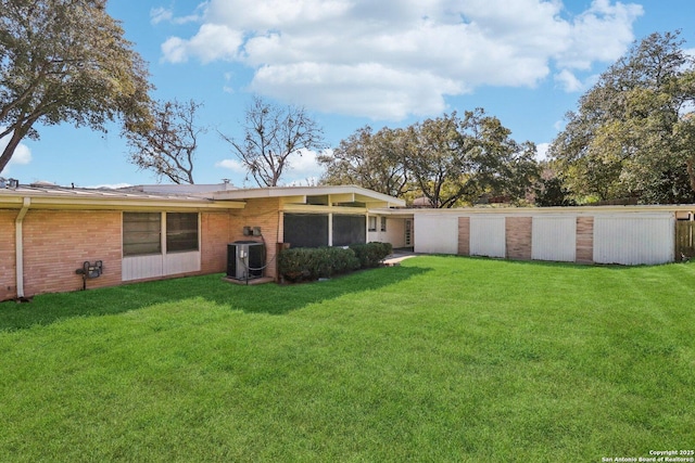 back of property featuring a yard, brick siding, and central AC