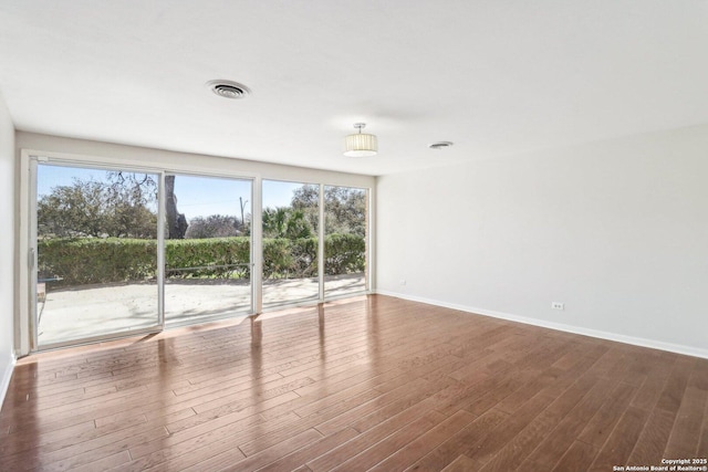 unfurnished room with visible vents, baseboards, and dark wood-style floors