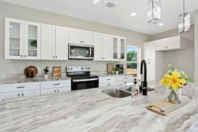 650 Canyon Cir, Canyon Lake, TX 78133 - kitchen featuring appliances with stainless steel finishes, a sink, light stone counters, white cabinetry, and decorative light fixtures