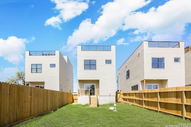rear view of property featuring a fenced backyard and a lawn