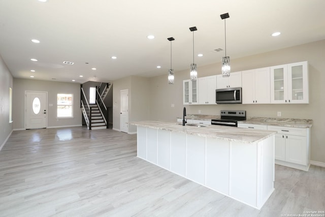 kitchen with light wood-style flooring, a sink, white cabinets, and stainless steel appliances