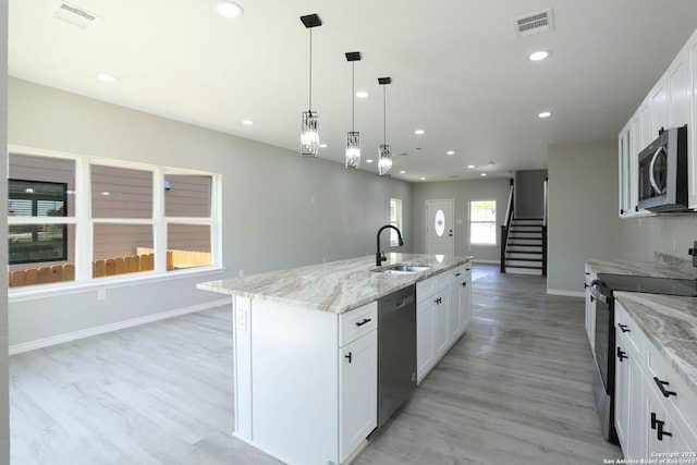 kitchen featuring recessed lighting, white cabinets, light wood-style floors, appliances with stainless steel finishes, and a sink