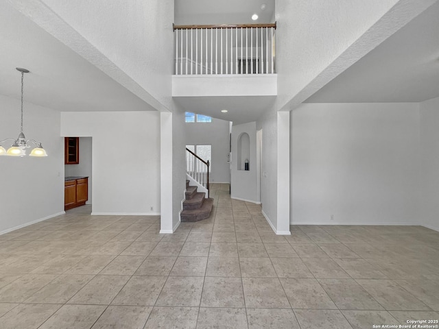 interior space featuring stairs, an inviting chandelier, light tile patterned floors, and baseboards