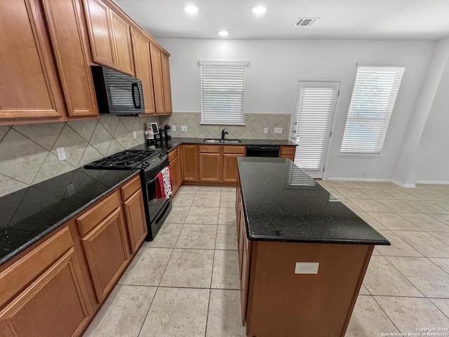 kitchen with a sink, tasteful backsplash, black appliances, and light tile patterned flooring