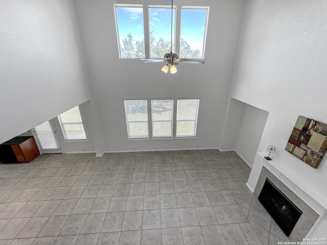 unfurnished living room with a healthy amount of sunlight, a fireplace, baseboards, and ceiling fan