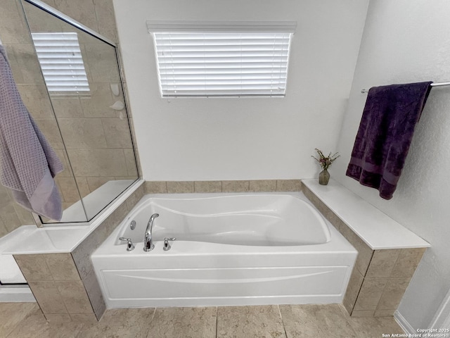 bathroom with a garden tub and a tile shower