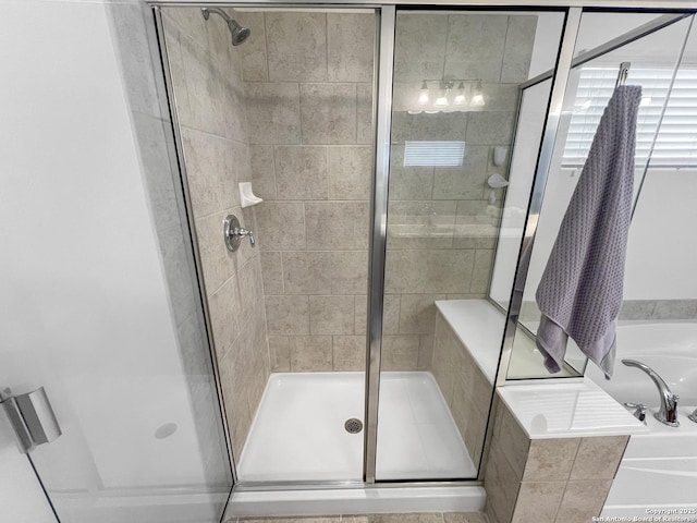 bathroom featuring a stall shower and a bath