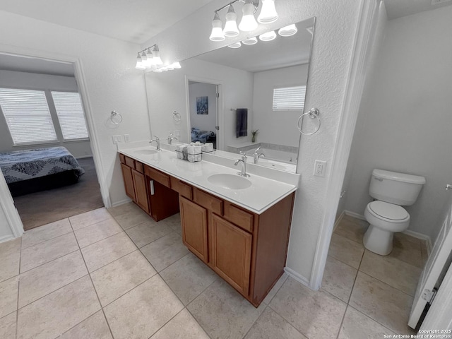 ensuite bathroom with a sink, ensuite bath, and tile patterned floors