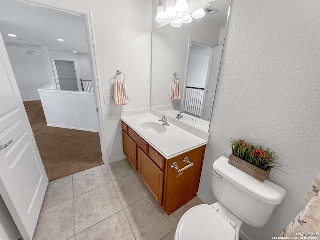 bathroom with vanity, tile patterned floors, toilet, and a textured wall