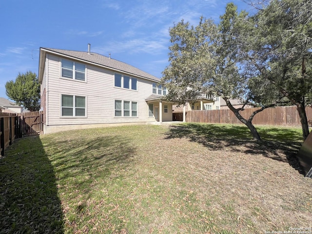 back of property with a fenced backyard and a lawn