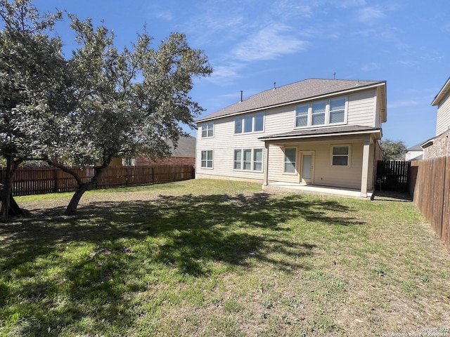 rear view of house with a lawn, a fenced backyard, and a patio area