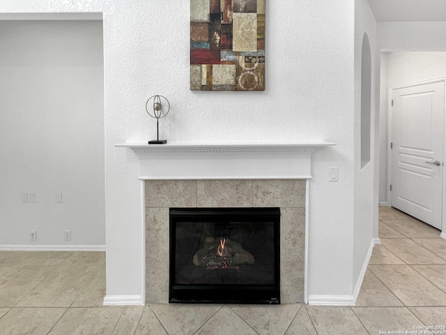 interior details featuring a tiled fireplace and baseboards