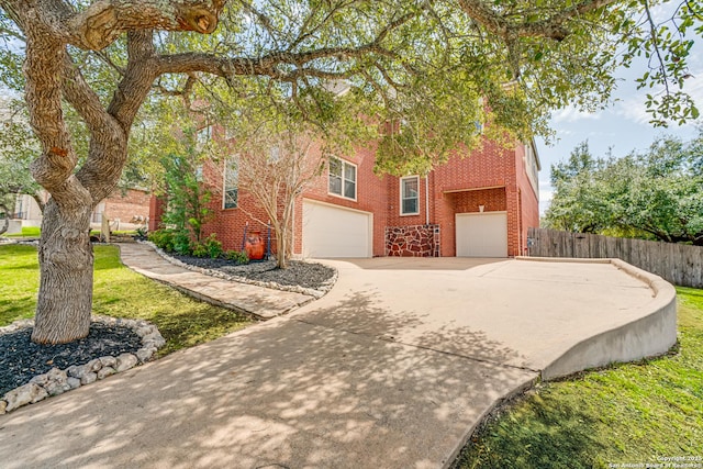 view of front of property featuring brick siding, an attached garage, concrete driveway, and fence