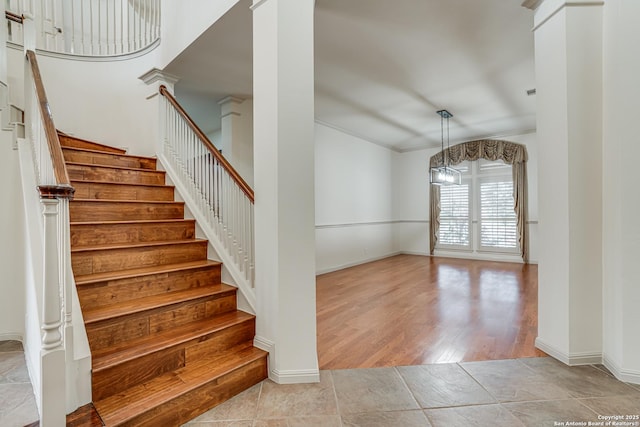 stairs featuring baseboards, ornate columns, and wood finished floors