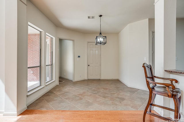 unfurnished dining area with a notable chandelier, visible vents, baseboards, and light tile patterned flooring