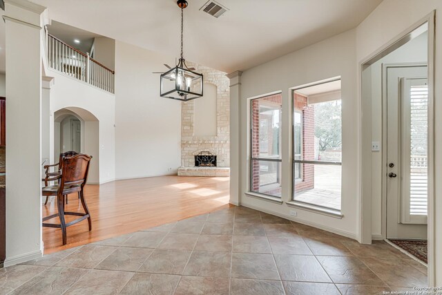 dining space featuring baseboards, visible vents, a fireplace, light wood-style floors, and a chandelier