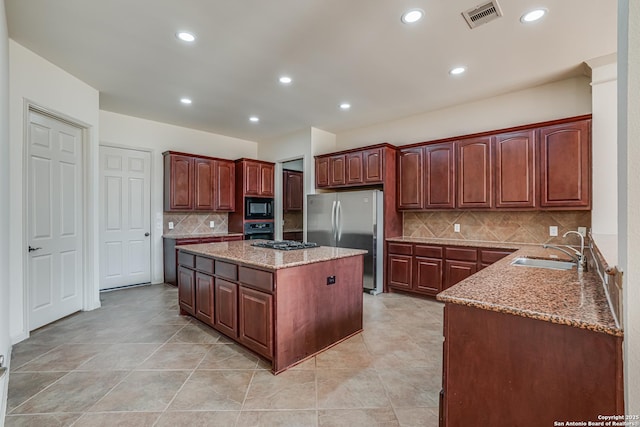 kitchen with a sink, visible vents, light stone counters, and black appliances