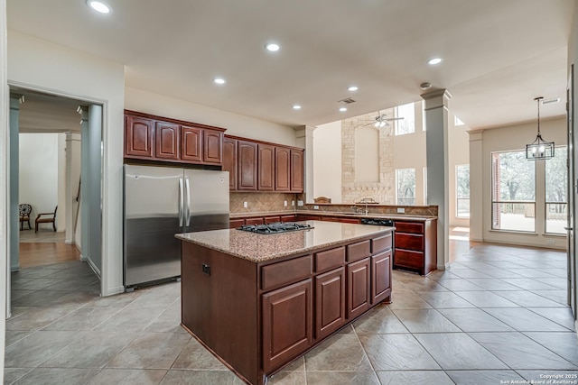 kitchen with a kitchen island, decorative columns, freestanding refrigerator, ceiling fan, and tasteful backsplash