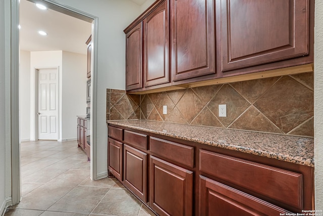 kitchen with light tile patterned floors, light stone countertops, baseboards, recessed lighting, and tasteful backsplash