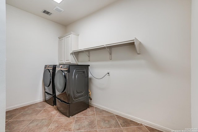 laundry area featuring visible vents, baseboards, washer and clothes dryer, light tile patterned floors, and cabinet space