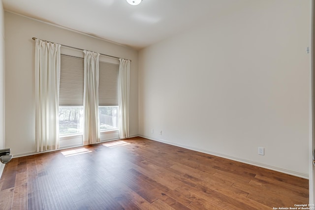 empty room with baseboards and wood finished floors