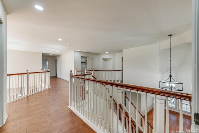 hall with hardwood / wood-style flooring, recessed lighting, an upstairs landing, and a chandelier