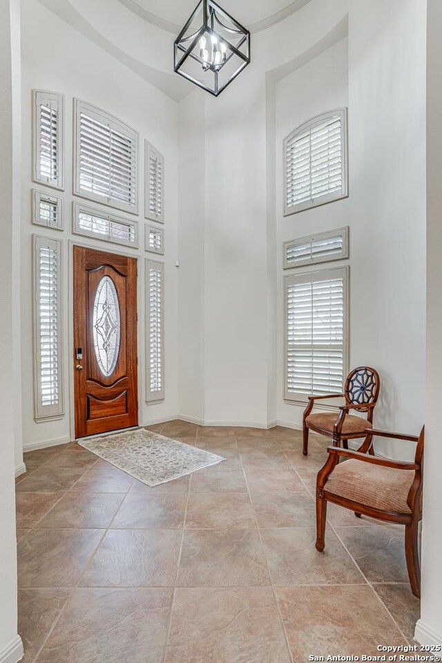 entrance foyer with a notable chandelier, baseboards, and a high ceiling