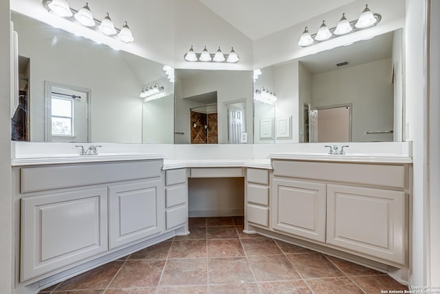 bathroom featuring lofted ceiling, double vanity, visible vents, and a sink